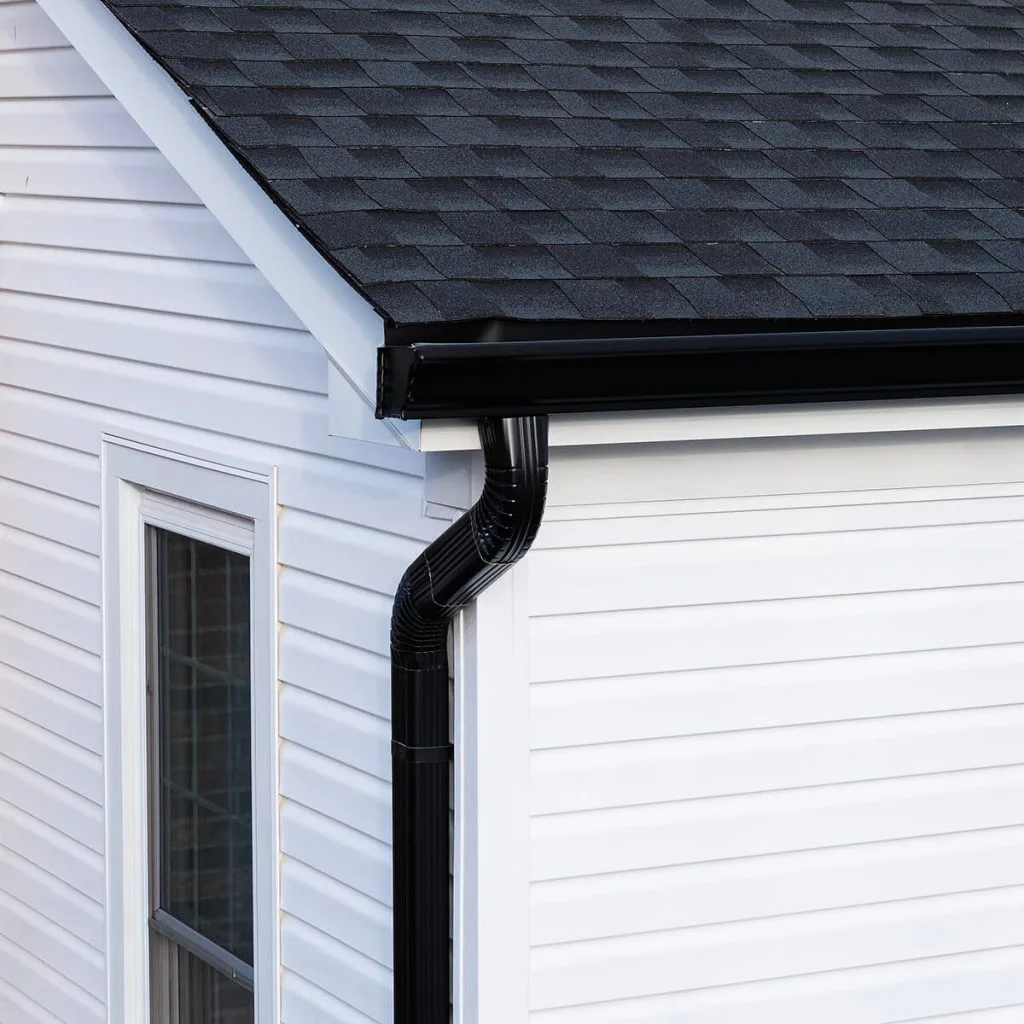 Black seamless gutters and downspout on white siding home