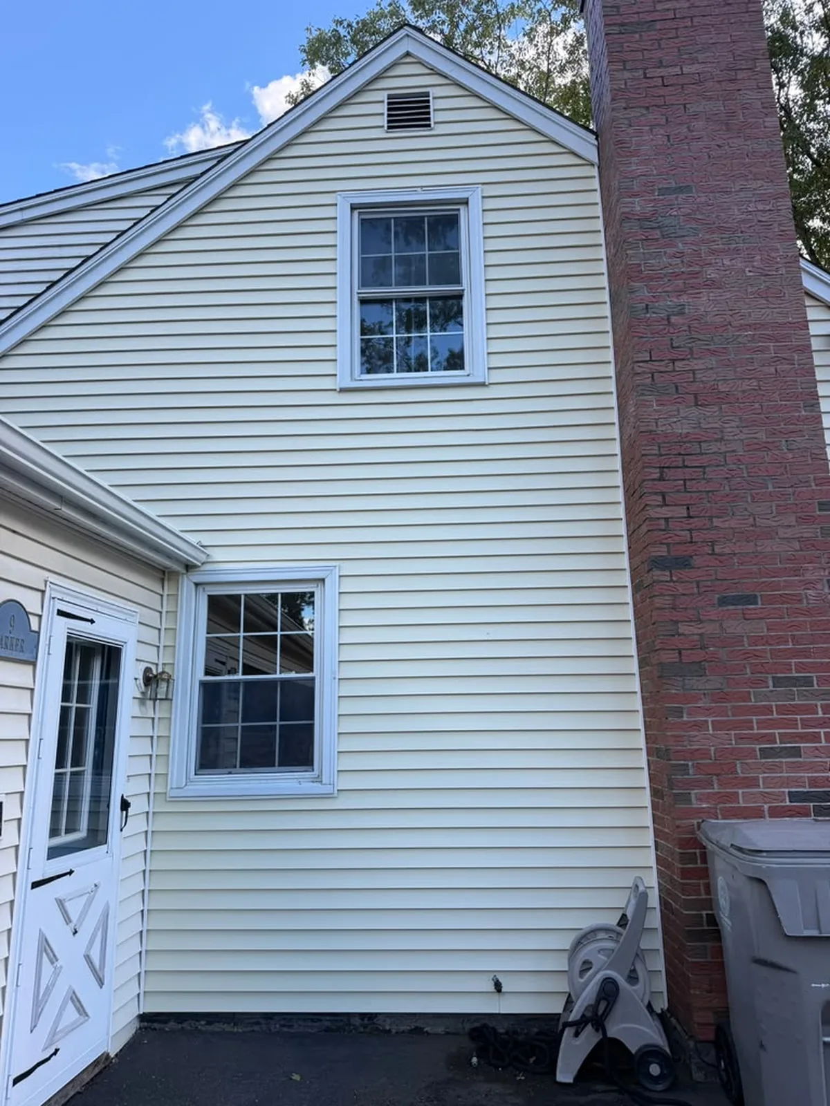 Cream vinyl siding with white trim and brick chimney