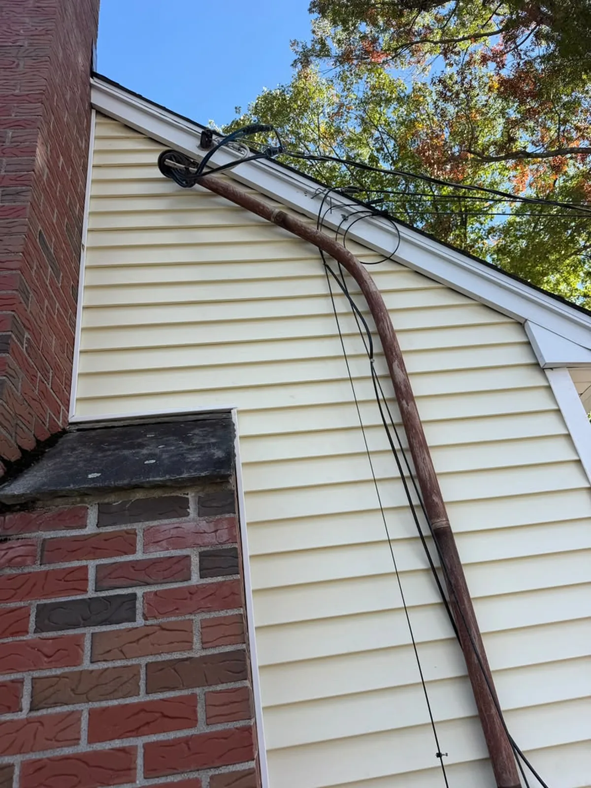 Cream vinyl siding corner with brick chimney
